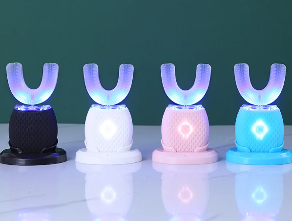 Quatre brosses à dents électrique en forme de U de différentes couleurs sur base lumineuse